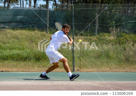 Tennis player hitting backhand at ball Tennis player hitting backhand at ball 113006169