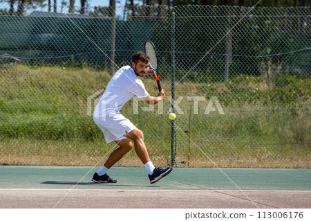 Tennis player hitting backhand at ball Tennis player hitting backhand at ball 113006176