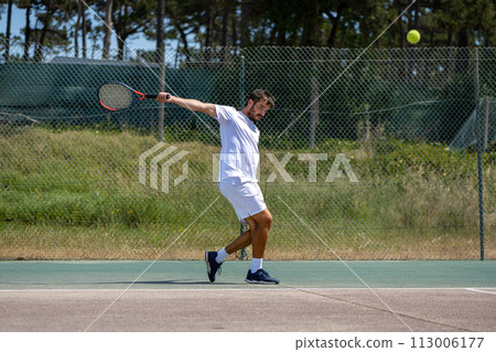 Tennis player hitting backhand at ball Tennis player hitting backhand at ball 113006177