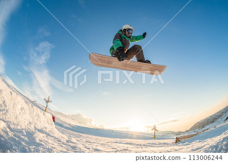 Snowboarder jumping against blue sky 113006244