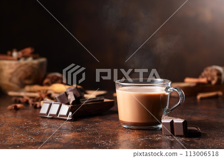 Glass of cocoa drink and pieces of dark chocolate on a brown vintage table. 113006518