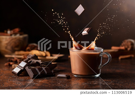 Pieces of dark chocolate fall into a glass of cocoa drink creating a beautiful splash. 113006519