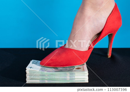 A female foot in a red high heel presses a bundle of money. A female foot in a red high heel presses a bundle of money. 113007396