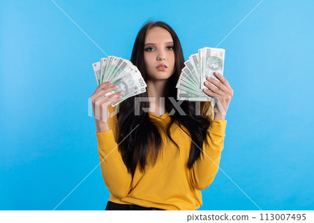 The young woman holds a fan of paper banknotes with a face value of one hundred zlotys. 113007495