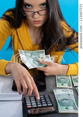 A rich young girl counts money at home at her desk for her next major financial investment. A rich young girl counts money at home at her desk for her next major financial investment. 113007555
