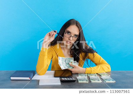 A rich young girl counts money at home at her desk for her next major financial investment. 113007561