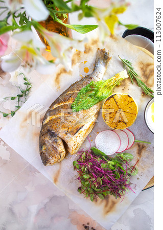 Grilled fish Dorado with lemon and herbs on a white background top view. Grilled fish Dorado with lemon and herbs on a white background top view. 113007624