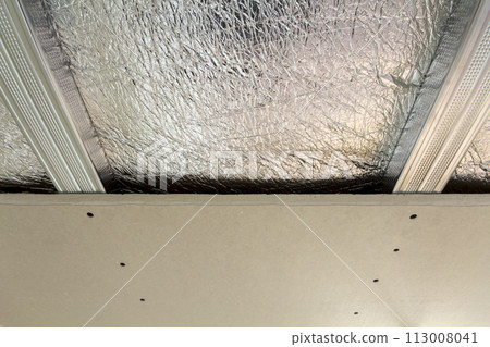 Room under construction with silver aluminum insulation foil and drywall on walls and ceiling. 113008041