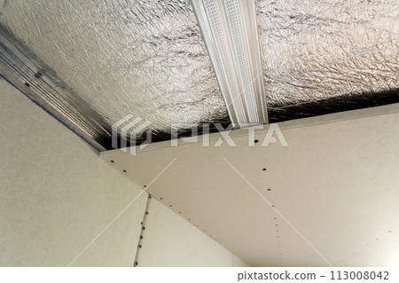 Room under construction with silver aluminum insulation foil and drywall on walls and ceiling. 113008042