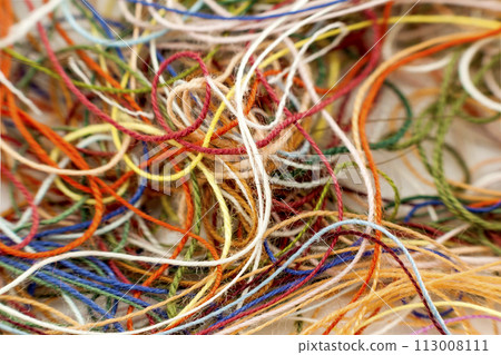 Multi-colored tangled colorful needlecraft silk thread rope. Macro shot. Abstract colors background Multi-colored tangled colorful needlecraft silk thread rope. Macro shot. Abstract colors background 113008111