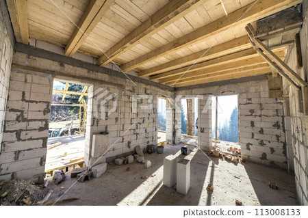 House room interior under construction and renovation. Energy saving walls of hollow foam insulation blocks, wooden ceiling beams and roof frame. 113008133