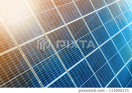 Close-up surface of lit by sun blue shiny solar photo voltaic panels. System producing renewable clean energy. Renewable ecological green energy production concept. Close-up surface of lit by sun blue shiny solar photo voltaic panels. System producing renewable clean energy. Renewable ecological green energy production concept. 113008155