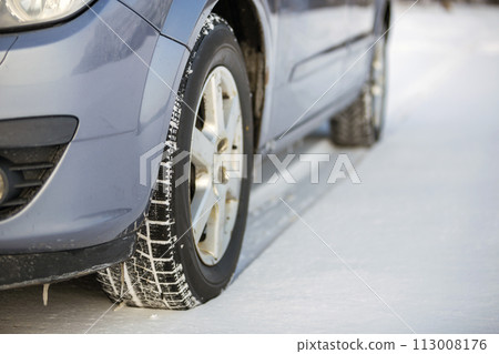Close up of a car tire parked on snowy road on winter day. Transportation and safety concept. Close up of a car tire parked on snowy road on winter day. Transportation and safety concept. 113008176