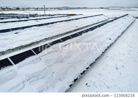 Aerial view of sustainable electrical power plant with solar photovoltaic panels covered with snow in winter for producing clean energy. Concept of low effectivity of renewable electricity in north 113008216