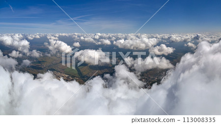 Aerial view from airplane window at high altitude of earth covered with white puffy cumulus clouds. Aerial view from airplane window at high altitude of earth covered with white puffy cumulus clouds. 113008335