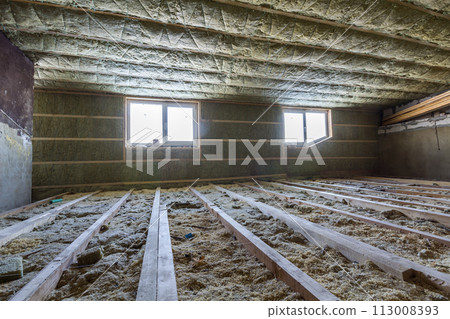 House attic under construction. Mansard walls and ceiling insulation with rock wool. Fiberglass insulation material in wooden frame for cold barrier House attic under construction. Mansard walls and ceiling insulation with rock wool. Fiberglass insulation material in wooden frame for cold barrier 113008393