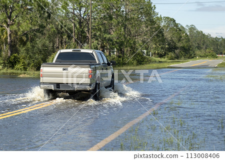 Flooded road in Florida after heavy hurricane rainfall. Evacuating cars and surrounded with water houses in suburban residential area Flooded road in Florida after heavy hurricane rainfall. Evacuating cars and surrounded with water houses in suburban residential area 113008406