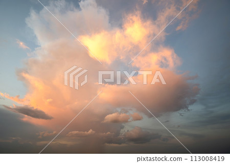 Dramatic moody sunset landscape with puffy clouds lit by yellow setting sun and blue sky. Dramatic moody sunset landscape with puffy clouds lit by yellow setting sun and blue sky. 113008419