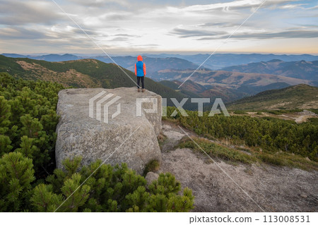 Young child boy hiker standing in mountains enjoying view of amazing mountain landscape. 113008531