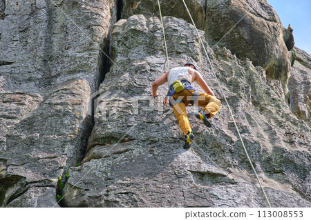 Strong male climber climbing steep wall of rocky mountain. Sportsman overcoming difficult route. Engaging in extreme sports hobby concept. Strong male climber climbing steep wall of rocky mountain. Sportsman overcoming difficult route. Engaging in extreme sports hobby concept. 113008553