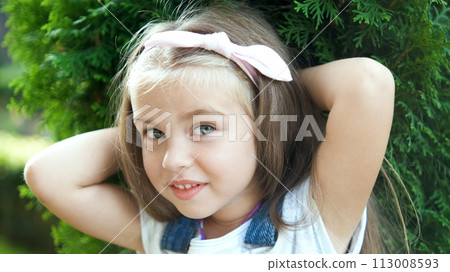 Portrait of pretty child girl standing outdoors in summer park smiling happily. 113008593