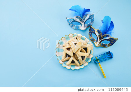 Jewish holiday Purim background with hamantaschen or hamans ears cookies, carnival mask and noisemaker 113009443