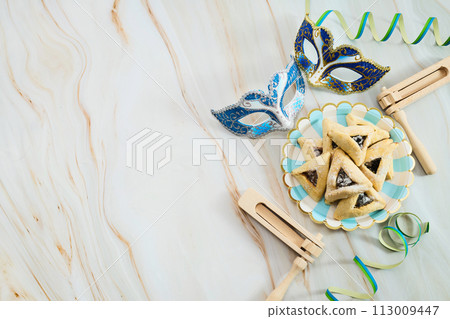 Jewish holiday Purim background with hamantaschen or hamans ears cookies, carnival mask and noisemaker 113009447
