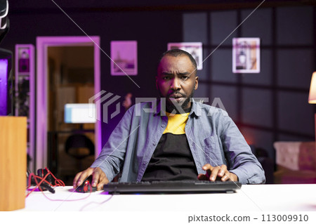 Upset african american gamer frustrated after losing online competitive multiplayer match playing on cutting edge gaming setup. BIPOC person feeling sad after being defeated in internet videogame 113009910