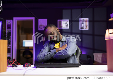 Gamer wincing while looking at computer monitor after losing singleplayer videogame, seeing game over screen. Man flinching seeing his character getting destroyed in difficult game level 113009922
