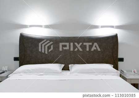 Minimal double bed with white mattress in luxury hotel bedroom. Comfortable bed 113010385