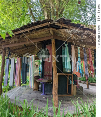 Thai wooden house in the garden with colorful cloth hanging on the wall Thai wooden house in the garden with colorful cloth hanging on the wall 113013560