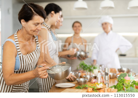 Lady while studying at culinary workshop, cooks appetizing sauce, marinade, dough in bowl. Lady while studying at culinary workshop, cooks appetizing sauce, marinade, dough in bowl. 113015550