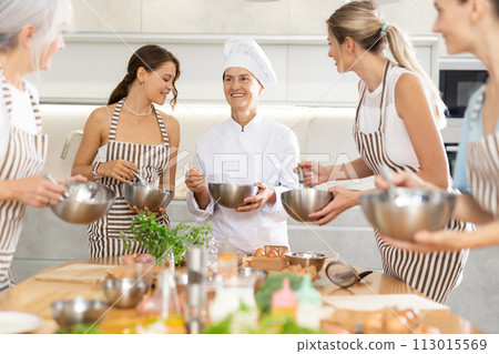 Mature female cook holding bowl and whisk 113015569