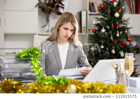 Female office worker doing paperwork during Christmastime Female office worker doing paperwork during Christmastime 113015575