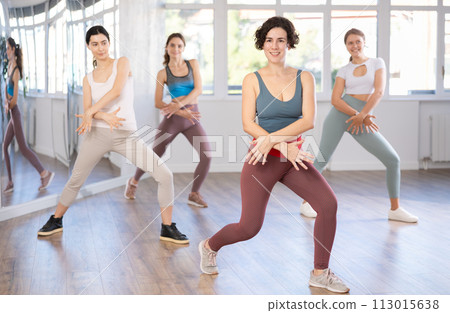 Hispanic woman learning modern street dancing during group class Hispanic woman learning modern street dancing during group class 113015638