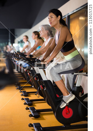 Woman on stationary bike workout in gym 113015725