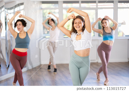 Smiling young woman enjoying vigorous dance at group class Smiling young woman enjoying vigorous dance at group class 113015727