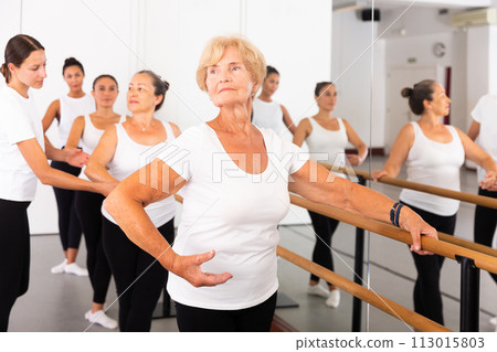 Dancing women stand in a ballet stance, where the choreographer helps to coordinate the movement Dancing women stand in a ballet stance, where the choreographer helps to coordinate the movement 113015803