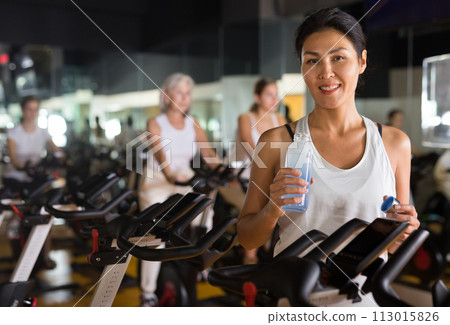 Woman standing with drinking water in gym Woman standing with drinking water in gym 113015826