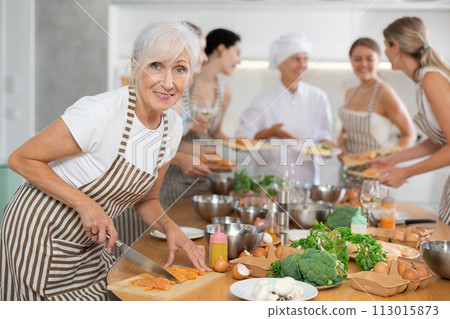 Elderly woman cooks chicken at master class 113015873