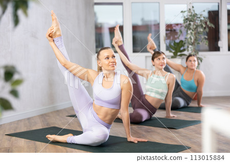 Three women doing yoga in fitness studio 113015884