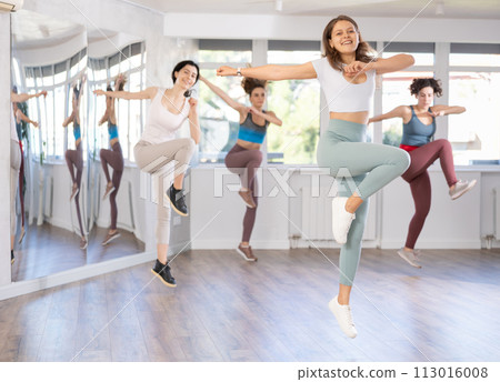 Cheerful girl captured jumping during lively dance fitness routine Cheerful girl captured jumping during lively dance fitness routine 113016008