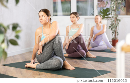 Young girl performing seated twisting asana Matsyendrasana Young girl performing seated twisting asana Matsyendrasana 113016013