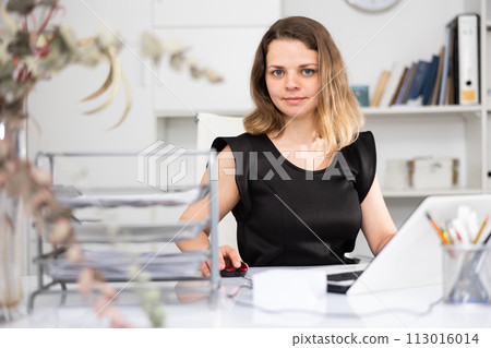 Portrait of female manager sitting at her desktop Portrait of female manager sitting at her desktop 113016014