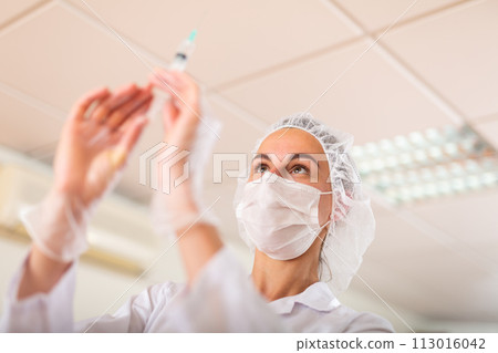 Nurse prepares a syringe for injection 113016042