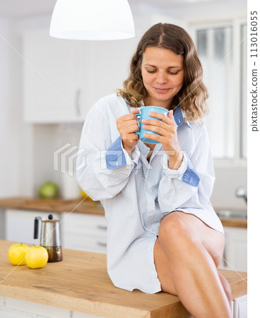 Smiling woman drinking coffee at home 113016055