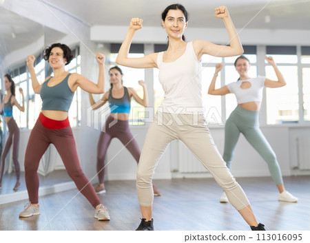 Positive women engaged in dancing in female group practices energetic swing in dance studio Positive women engaged in dancing in female group practices energetic swing in dance studio 113016095