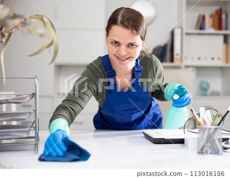 Woman cleaner polishing table in office 113016186