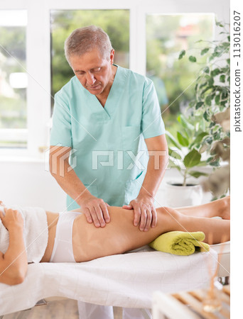 Skilled old masseur conducting hip massage for woman client Skilled old masseur conducting hip massage for woman client 113016207