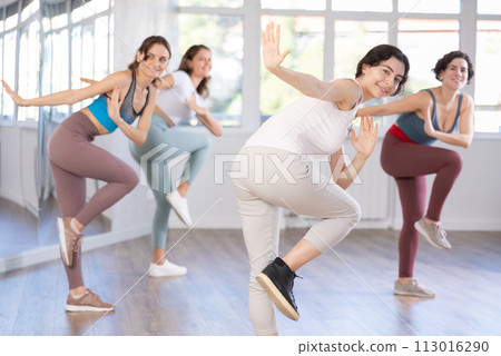 Smiling young woman enjoying vigorous dance at group class Smiling young woman enjoying vigorous dance at group class 113016290